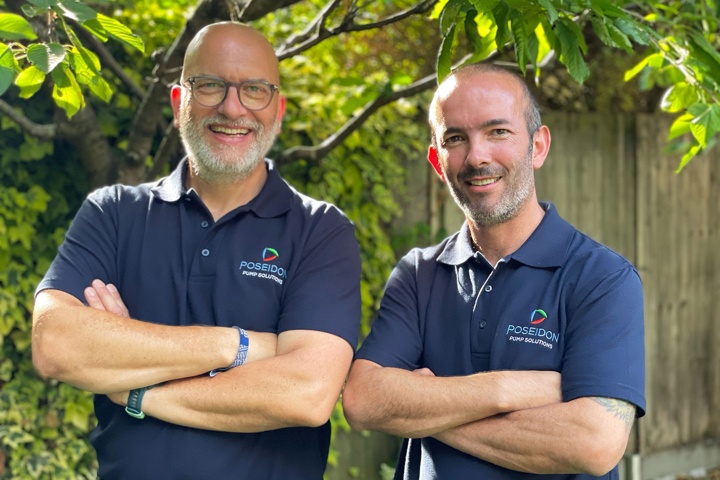 Two men wearing Poseidon Pump Solutions shirts outdoors